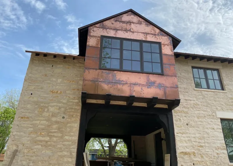 Copper metal panel facade on a stone building for Roof Repair in Zimmerman